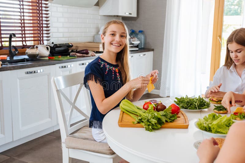 Hübsche Jugendliche, die ein gamburger in der Küche machen stockfoto Hübsche Jugendliche, die ein gamburger in der Küche machen stockfoto