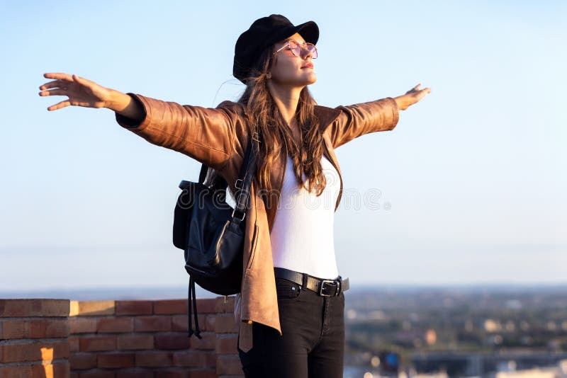Hübsche junge Frau, die sich auf der Dachterrasse amüsiert und dabei Zeit und Sonnenuntergang genießt lizenzfreie stockfotos Hübsche junge Frau, die sich auf der Dachterrasse amüsiert und dabei Zeit und Sonnenuntergang genießt lizenzfreie stockfotos