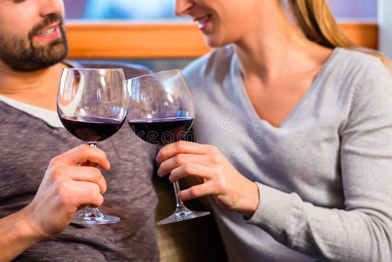 Hübsche Paare, die zu Hause Rotwein trinken lizenzfreie stockfotos Hübsche Paare, die zu Hause Rotwein trinken lizenzfreie stockfotos