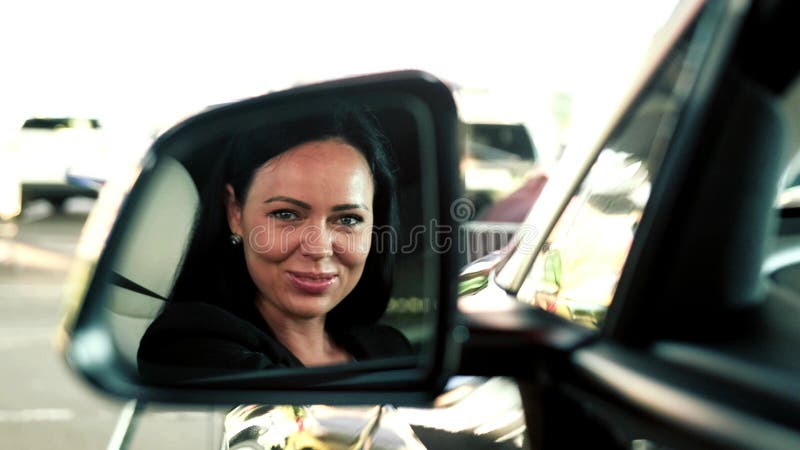Hübsche Reflexion des weiblichen Fahrers im Blick auf den Auto. Konzept der Sicherheit im Reiseverkehr. lizenzfreies stockbild