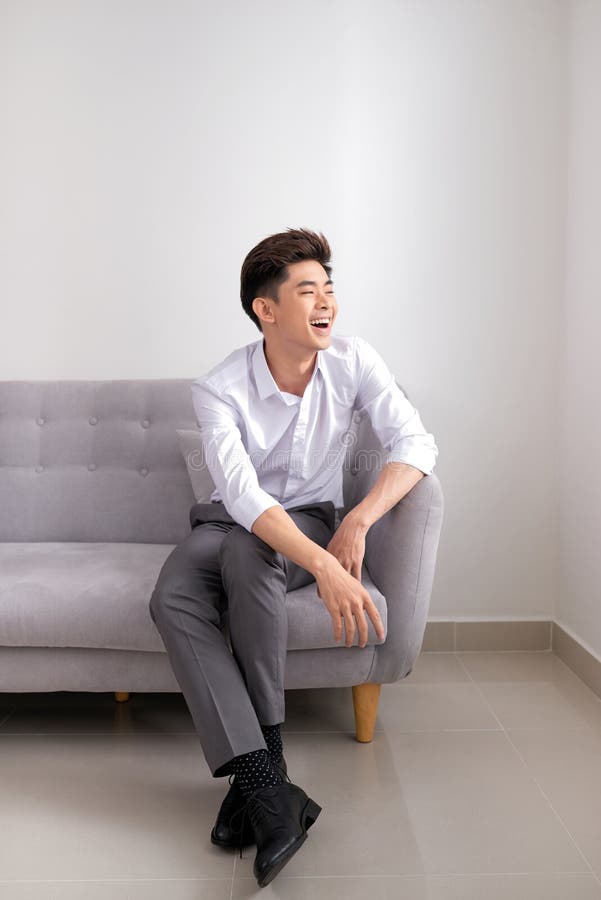 Hübscher asiatischer Mann, der zu Hause auf Sofa, Lächeln glücklich sitzt lizenzfreie stockfotografie Hübscher asiatischer Mann, der zu Hause auf Sofa, Lächeln glücklich sitzt lizenzfreie stockfotografie