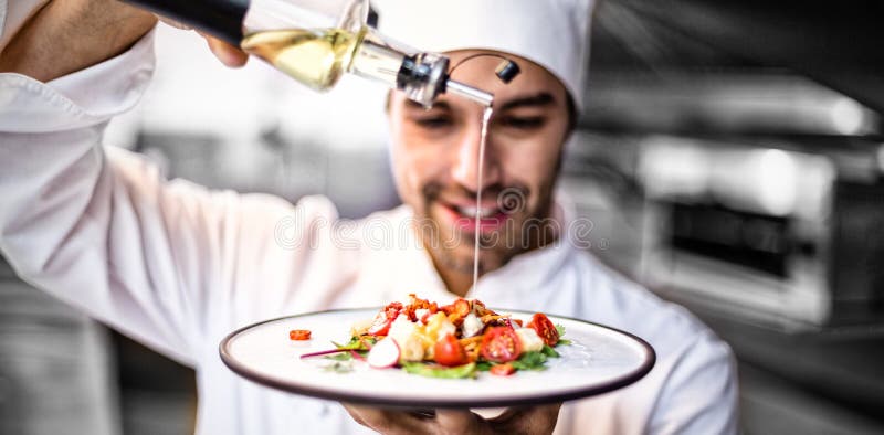 Hübscher Chef, der Olivenöl auf Mahlzeit gießt lizenzfreie stockfotografie Hübscher Chef, der Olivenöl auf Mahlzeit gießt lizenzfreie stockfotografie