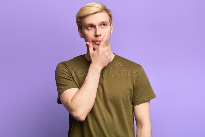 Hübscher ernster junger Mann, der oben mit durchdachtem Blick schaut stockfoto Hübscher ernster junger Mann, der oben mit durchdachtem Blick schaut stockfoto