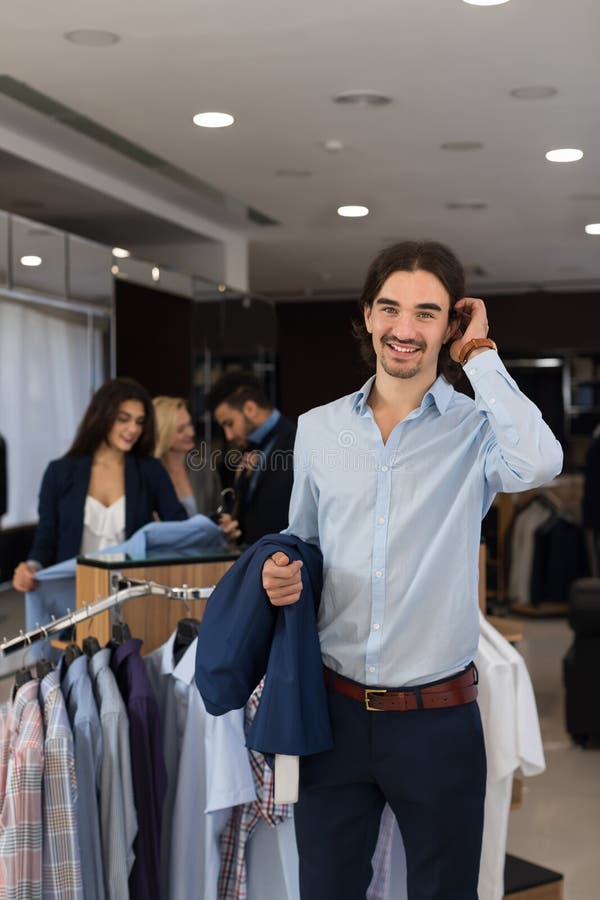 Hübscher Geschäftsmann-Abnutzungs-Gesellschaftsanzug, der Jacke in den Händen im modernen Männerkleidungs-Shop hält lizenzfreie stockfotos Hübscher Geschäftsmann-Abnutzungs-Gesellschaftsanzug, der Jacke in den Händen im modernen Männerkleidungs-Shop hält lizenzfreie stockfotos