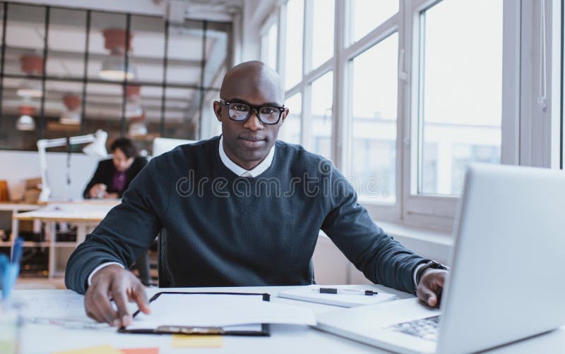 Hübscher junger afrikanischer Mann an seinem Schreibtisch mit Laptop stockfotos Hübscher junger afrikanischer Mann an seinem Schreibtisch mit Laptop stockfotos