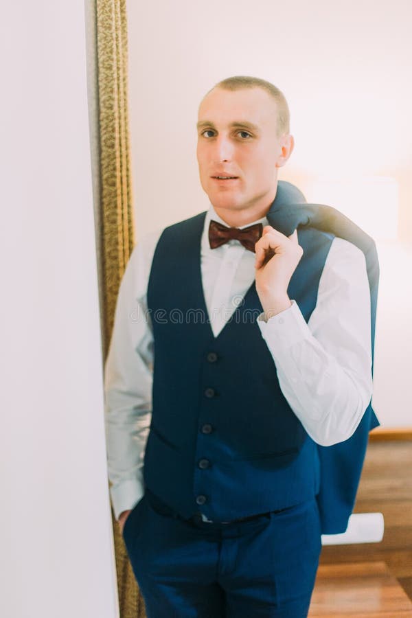 Hübscher junger athletischer Mann des kurzen Haares kleidete in der blauen Klagenaufstellung an, die Innen ist und hielt Blazer ü lizenzfreies stockbild Hübscher junger athletischer Mann des kurzen Haares kleidete in der blauen Klagenaufstellung an, die Innen ist und hielt Blazer ü lizenzfreies stockbild