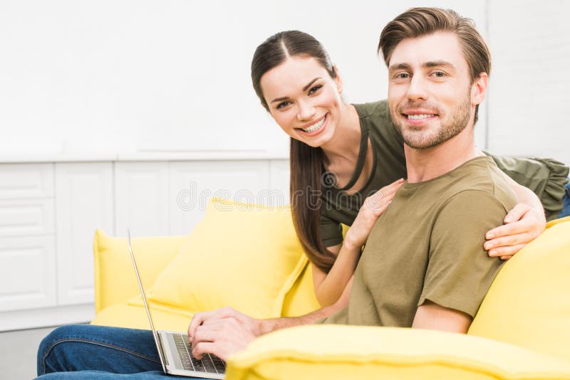 Hübscher junger Mann, der zu Hause mit Laptop während seine Freundin arbeitet stockbilder