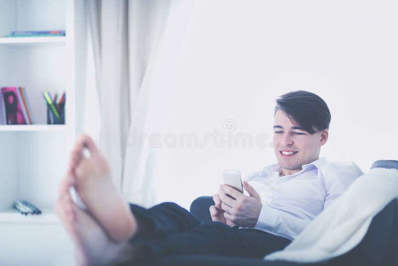 Hübscher junger Mann, der zu Hause Smartphone verwendet lizenzfreies stockbild Hübscher junger Mann, der zu Hause Smartphone verwendet lizenzfreies stockbild