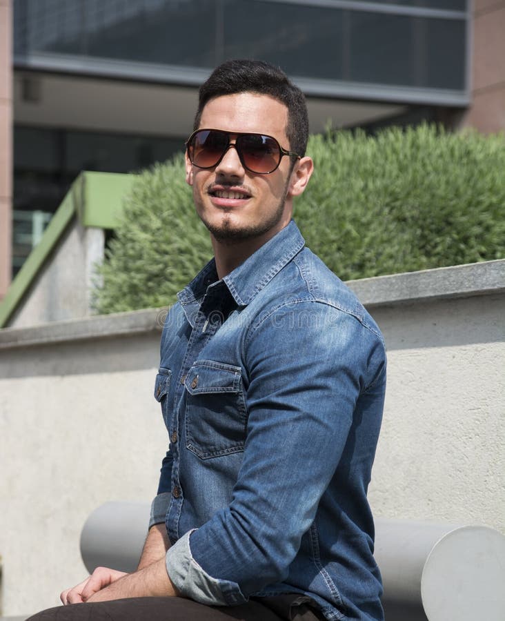 Hübscher junger Mann mit Denimhemd und -Sonnenbrille stockfoto Hübscher junger Mann mit Denimhemd und -Sonnenbrille stockfoto