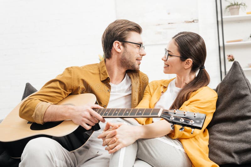 Hübscher junger Mann mit der Gitarre, die mit Freundin flirtet lizenzfreie stockfotos