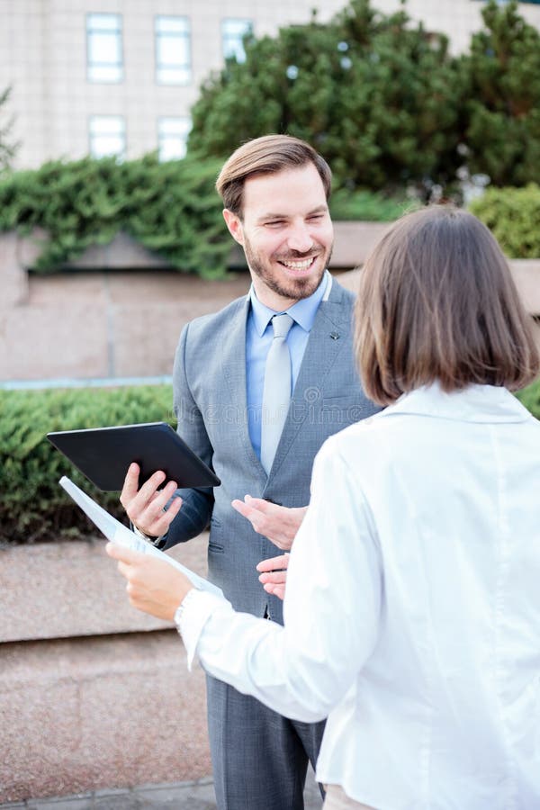 Hübscher junger Mann und weibliche Geschäftsleute, die vor einem Bürogebäude, eine Sitzung und eine Diskussion habend sprechen stockbilder Hübscher junger Mann und weibliche Geschäftsleute, die vor einem Bürogebäude, eine Sitzung und eine Diskussion habend sprechen stockbilder