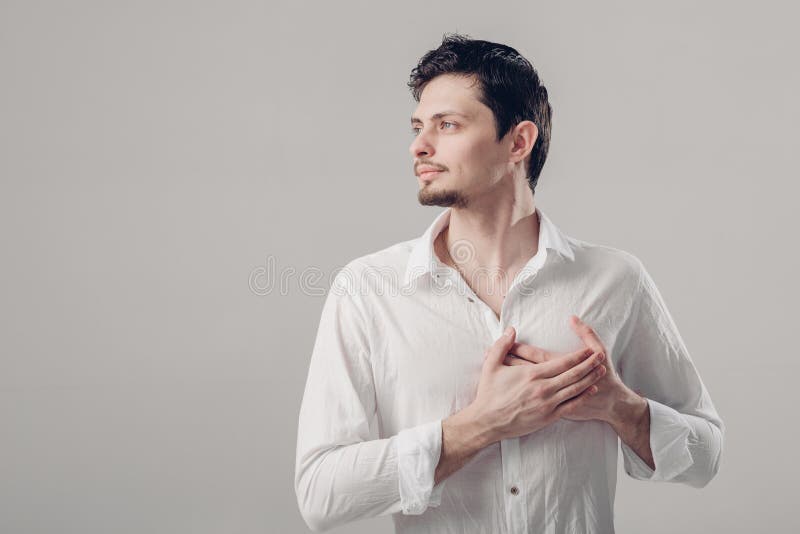 Hübscher junger stolzer Mann im Hemd, das Hand auf Kasten auf Grau hält stockbild
