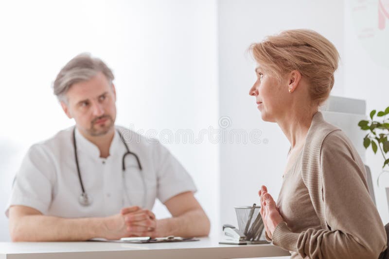 Hübscher Mittelalterdoktor und weiblicher Patient im Krankenhausbüro lizenzfreie stockbilder Hübscher Mittelalterdoktor und weiblicher Patient im Krankenhausbüro lizenzfreie stockbilder