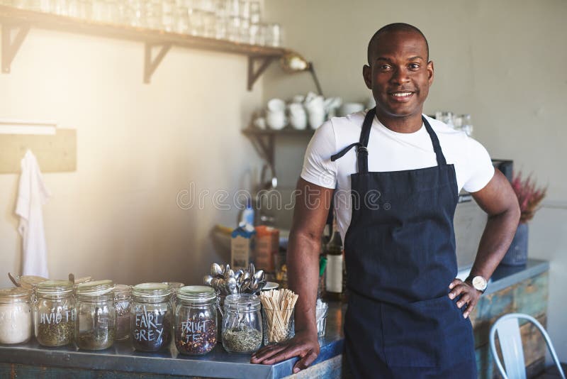 Hübscher schwarzer Unternehmer steht Cafézähler bereit