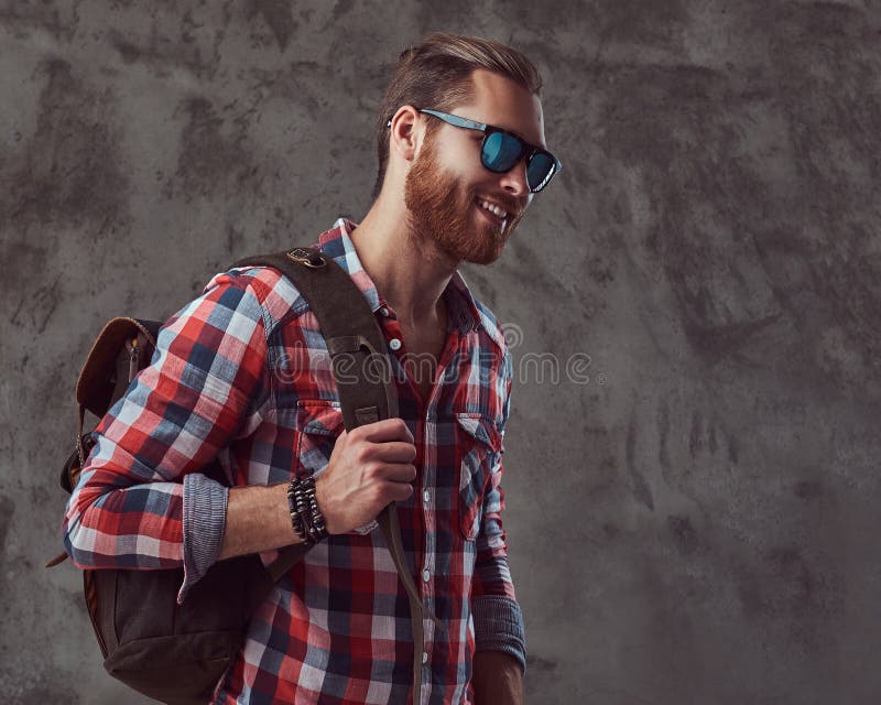 Hübscher stilvoller Rothaarigereisender in einem Flanellhemd und -Sonnenbrille mit einem Rucksack, werfend in einem Studio auf ei stockfoto Hübscher stilvoller Rothaarigereisender in einem Flanellhemd und -Sonnenbrille mit einem Rucksack, werfend in einem Studio auf ei stockfoto