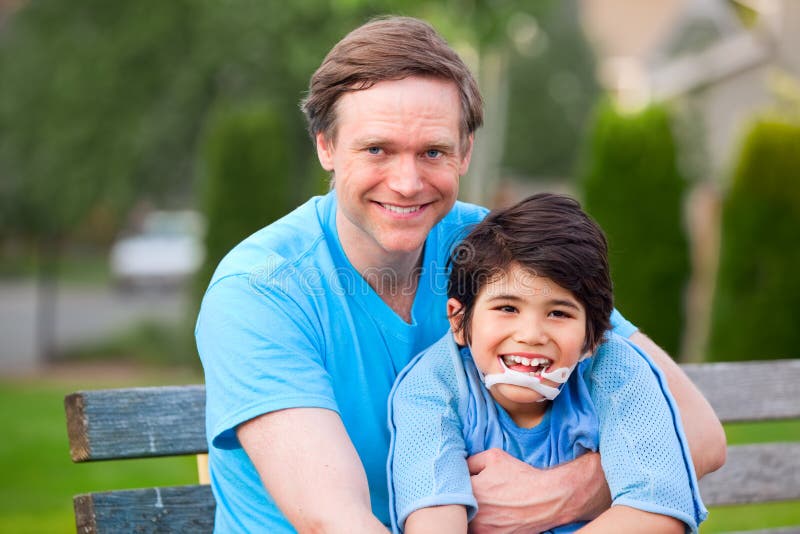 Hübscher Vater, der draußen lächelnden arbeitsunfähigen Sohn hält stockfoto Hübscher Vater, der draußen lächelnden arbeitsunfähigen Sohn hält stockfoto