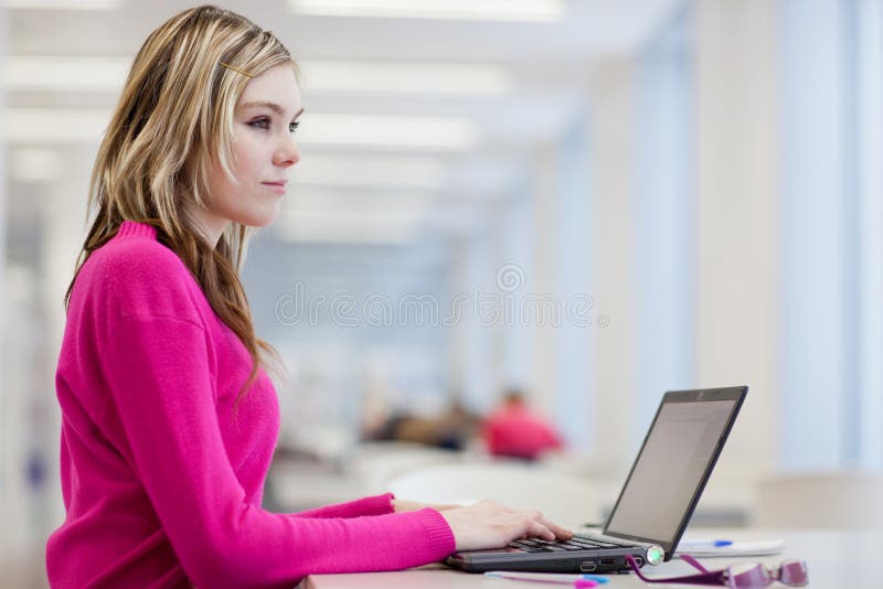 Hübscher, weiblicher Kursteilnehmer mit Laptop und Bücher lizenzfreie stockbilder