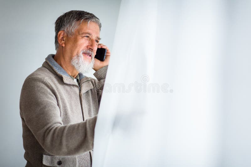 Hübscher älterer Mann, der um seinen Handy ersucht stockfoto Hübscher älterer Mann, der um seinen Handy ersucht stockfoto
