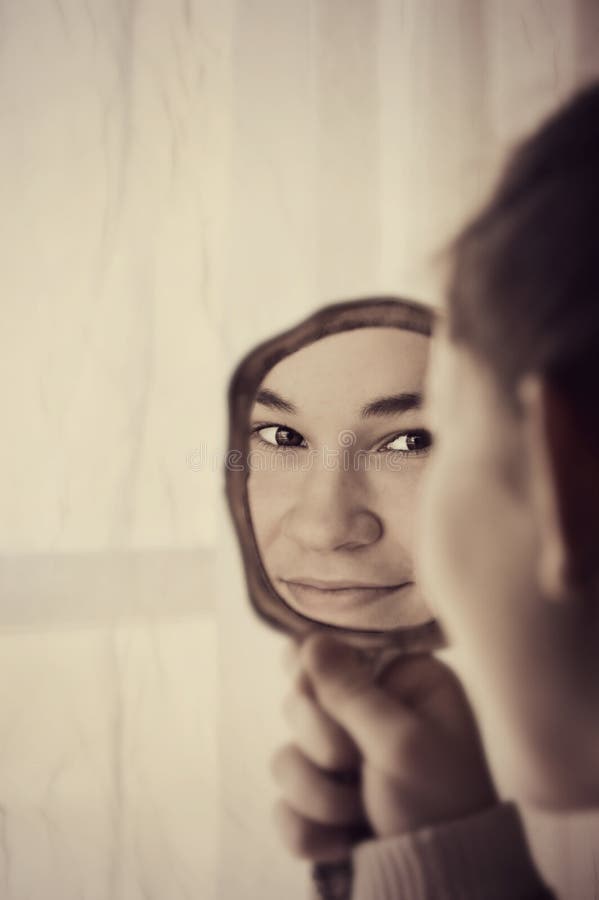 A beautiful, young, teenager looking at her reflection in a hand held mirror. A beautiful, young, teenager looking at her reflection in a hand held mirror.