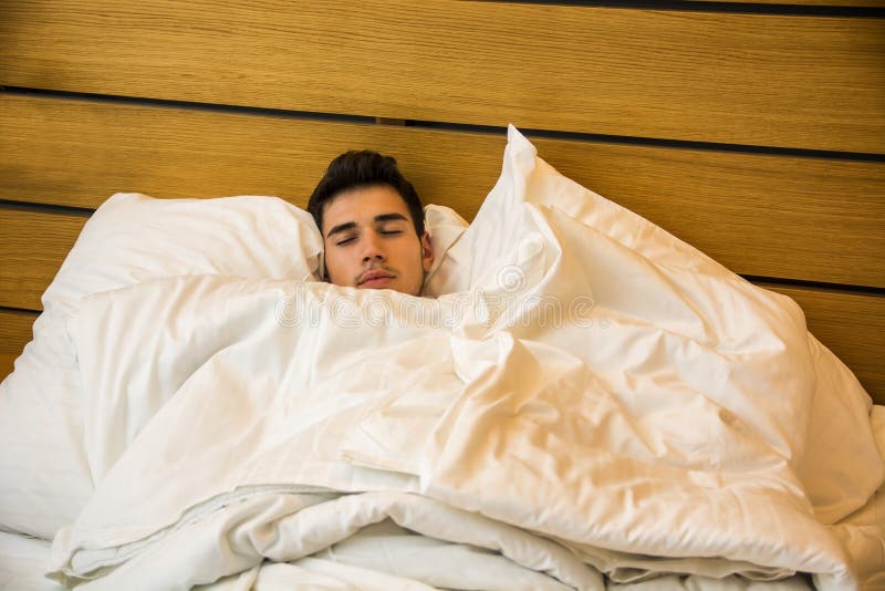 Hübsches männliches Modell, das allein auf seinem Bett liegt lizenzfreies stockfoto Hübsches männliches Modell, das allein auf seinem Bett liegt lizenzfreies stockfoto