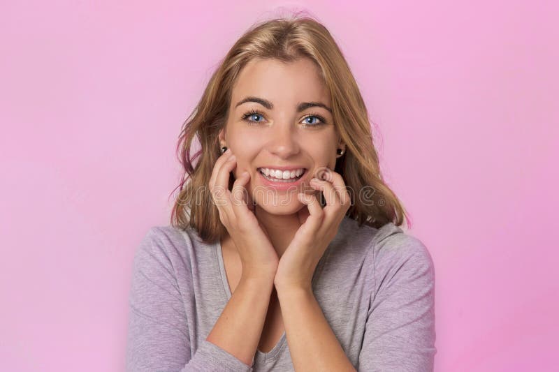 Portrait of young pretty and attractive blond Caucasian girl with beautiful blue eyes on her 20s excited and happy smiling cheerful in sweet face expression isolated on pink background. Portrait of young pretty and attractive blond Caucasian girl with beautiful blue eyes on her 20s excited and happy smiling cheerful in sweet face expression isolated on pink background