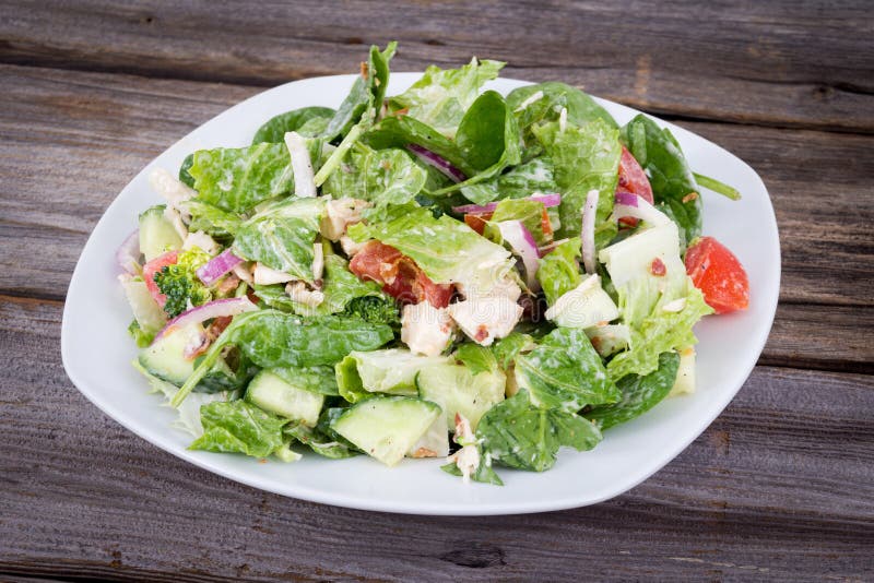 Hühner- und Gemüsesalat mit der Ranch, die über hölzerner Rückseite ankleidet lizenzfreies stockbild Hühner- und Gemüsesalat mit der Ranch, die über hölzerner Rückseite ankleidet lizenzfreies stockbild