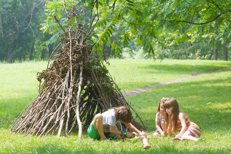 I bambini che giocano accanto al bastone di legno alloggiano assomigliare alla capanna indiana, fotografia stock libera da diritti I bambini che giocano accanto al bastone di legno alloggiano assomigliare alla capanna indiana, fotografia stock libera da diritti