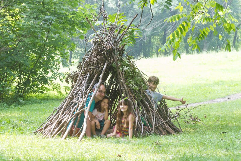 I bambini che giocano accanto al bastone di legno alloggiano assomigliare alla capanna indiana, immagine stock I bambini che giocano accanto al bastone di legno alloggiano assomigliare alla capanna indiana, immagine stock