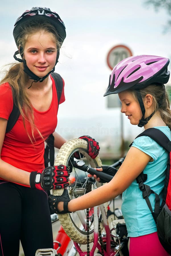 I bambini delle ragazze che ciclano la famiglia pompano sulla gomma della bicicletta fotografia stock I bambini delle ragazze che ciclano la famiglia pompano sulla gomma della bicicletta fotografia stock