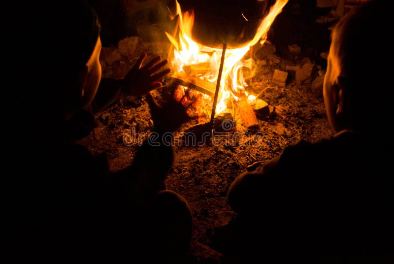 I bambini si siedono intorno al fuoco di accampamento alla notte fotografie stock libere da diritti I bambini si siedono intorno al fuoco di accampamento alla notte fotografie stock libere da diritti