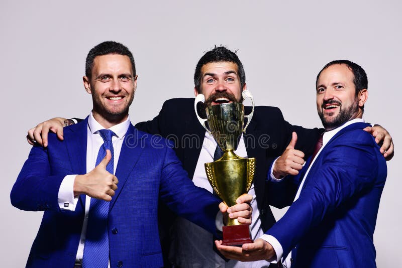 I capi della società tengono il premio, i pollici di manifestazione su e l'abbraccio dorati fotografia stock I capi della società tengono il premio, i pollici di manifestazione su e l'abbraccio dorati fotografia stock