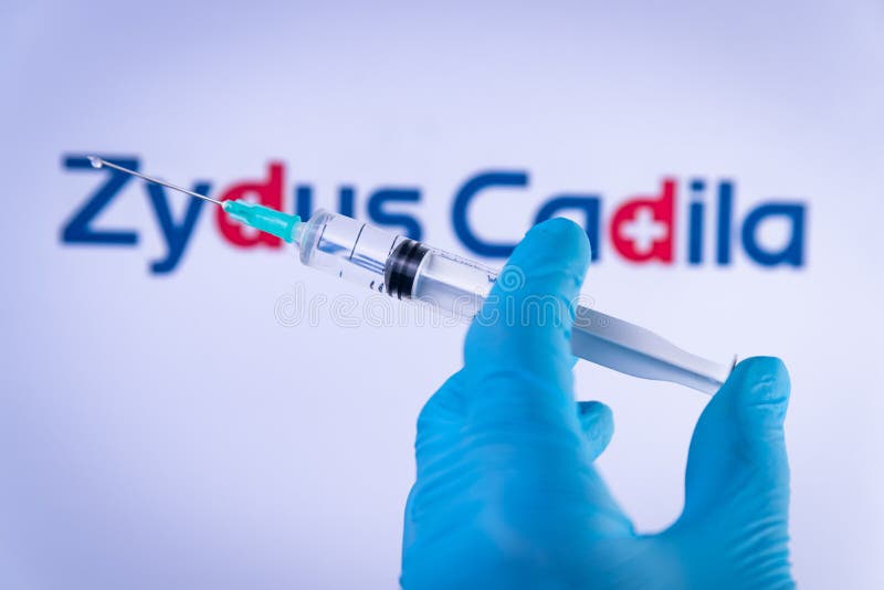 In this photo illustration a hand in medical gloves hold a syringe in front of Zydus Cadila logo in Barcelona, Spain on September 2, 2021. Zydus Cadila is an indian company developing the Covid-19 vaccine CNBC-TV18, also know as  -D. In this photo illustration a hand in medical gloves hold a syringe in front of Zydus Cadila logo in Barcelona, Spain on September 2, 2021. Zydus Cadila is an indian company developing the Covid-19 vaccine CNBC-TV18, also know as  -D