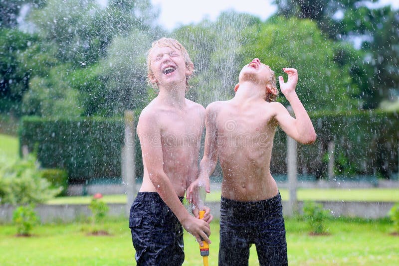 I due fratelli che giocano con acqua annaffiano nel giardino fotografia stock libera da diritti I due fratelli che giocano con acqua annaffiano nel giardino fotografia stock libera da diritti