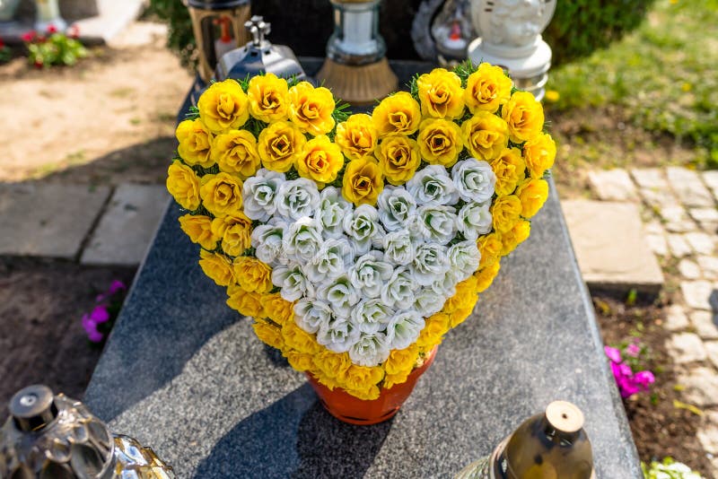 I fiori artificiali sotto forma di un cuore ed i candelieri si trovano sulla pietra tombale nel cimitero immagine stock I fiori artificiali sotto forma di un cuore ed i candelieri si trovano sulla pietra tombale nel cimitero immagine stock
