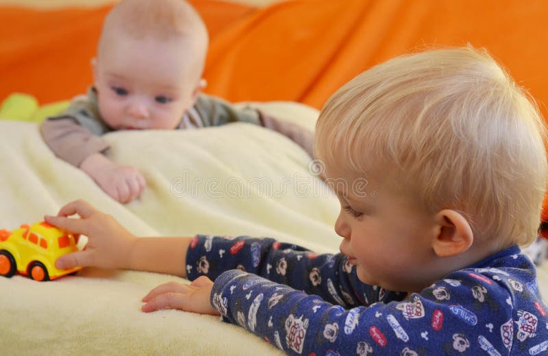 I fratelli germani godono di dei giocattoli Il bambino sta guardando il fratello più anziano fotografie stock I fratelli germani godono di dei giocattoli Il bambino sta guardando il fratello più anziano fotografie stock