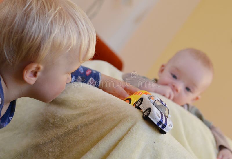 I fratelli germani godono di dei giocattoli Il bambino sta guardando il fratello più anziano immagini stock libere da diritti I fratelli germani godono di dei giocattoli Il bambino sta guardando il fratello più anziano immagini stock libere da diritti