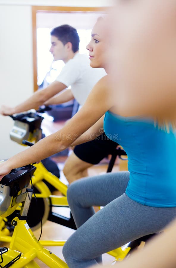 I giovani con forma fisica vanno in bicicletta nella palestra fotografia stock I giovani con forma fisica vanno in bicicletta nella palestra fotografia stock