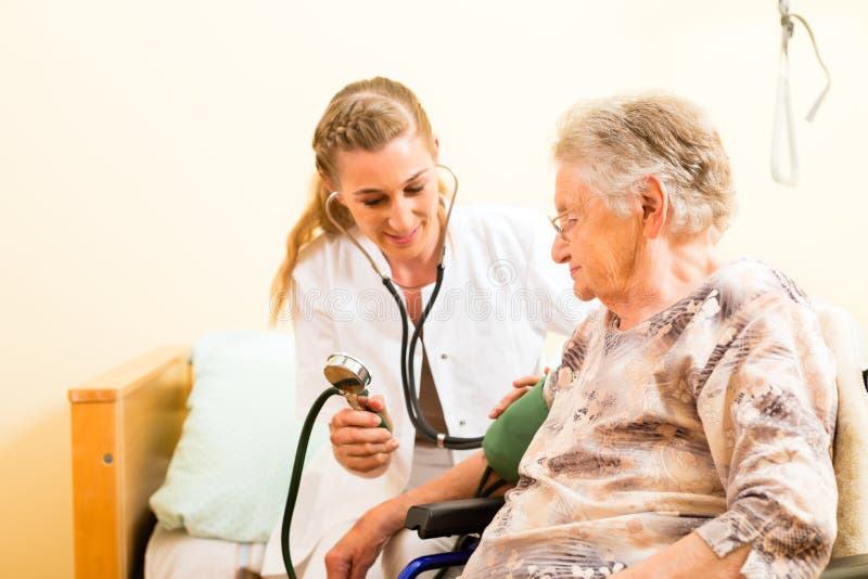 Young nurse and female senior in nursing home, the blood pressure is going to be measured. Young nurse and female senior in nursing home, the blood pressure is going to be measured