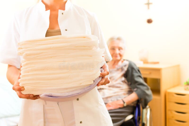 Young nurse and female senior in nursing home, the towels going to be changed. Young nurse and female senior in nursing home, the towels going to be changed