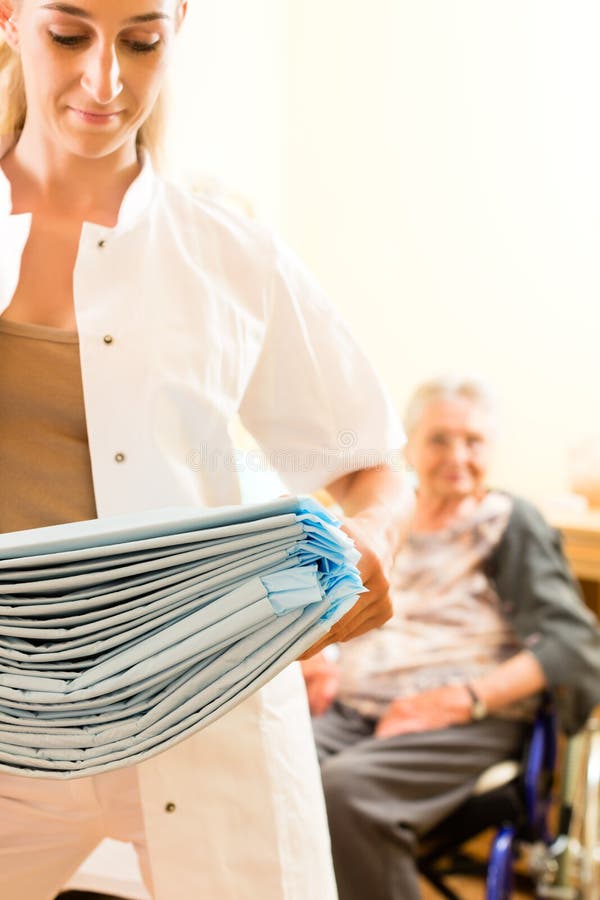 Young nurse and female senior in nursing home, the towels going to be changed. Young nurse and female senior in nursing home, the towels going to be changed