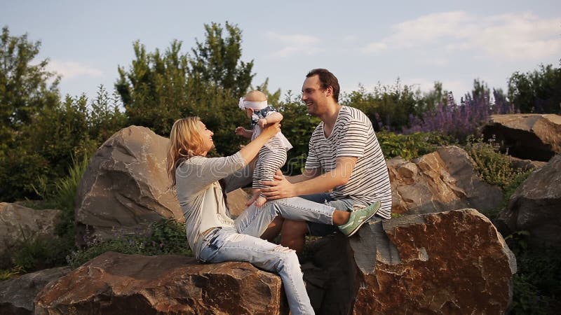 I giovani genitori con una figlia giocano nel parco al tramonto