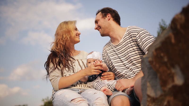 I giovani genitori con una figlia giocano nel parco al tramonto