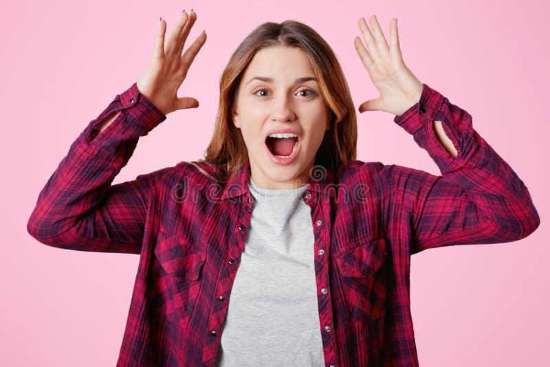 I giovani gesti femminili infastiditi emozionali attivamente, si tiene per mano nel gesto furioso, grida irosamente, vestito con fotografia stock I giovani gesti femminili infastiditi emozionali attivamente, si tiene per mano nel gesto furioso, grida irosamente, vestito con fotografia stock