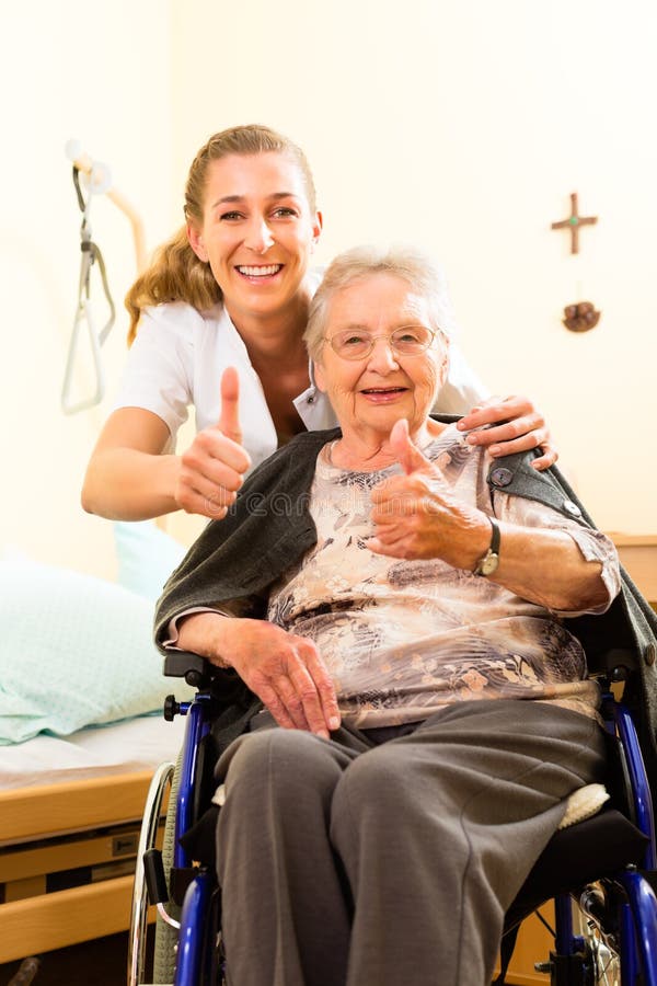 Young nurse and female senior in nursing home, the old lady sitting in a wheel chair. Young nurse and female senior in nursing home, the old lady sitting in a wheel chair