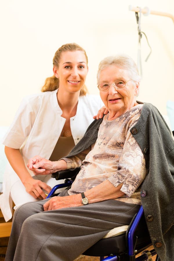 Young nurse and female senior in nursing home, the old lady sitting in a wheel chair. Young nurse and female senior in nursing home, the old lady sitting in a wheel chair