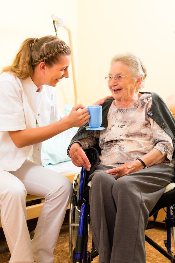 Young nurse and female senior in nursing home, the old lady sitting in a wheel chair. Young nurse and female senior in nursing home, the old lady sitting in a wheel chair