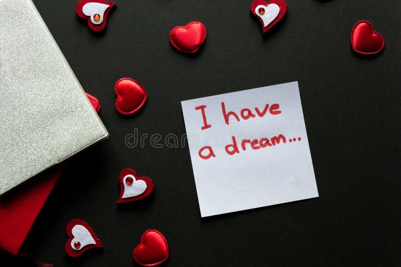 I have a dream. Love concept - valentine&x27;s day background. Red hearts and paper wit hand writing on black