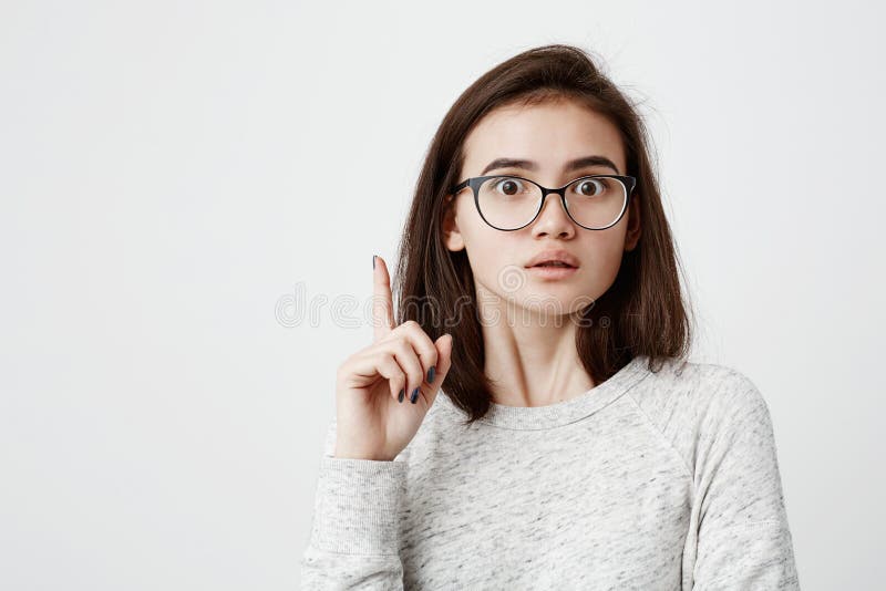 I have a great idea! Smart quick-witted pretty girl with dark hair wearing eyeglasses keeping finger pointed upwards stock photo I have a great idea! Smart quick-witted pretty girl with dark hair wearing eyeglasses keeping finger pointed upwards stock photo