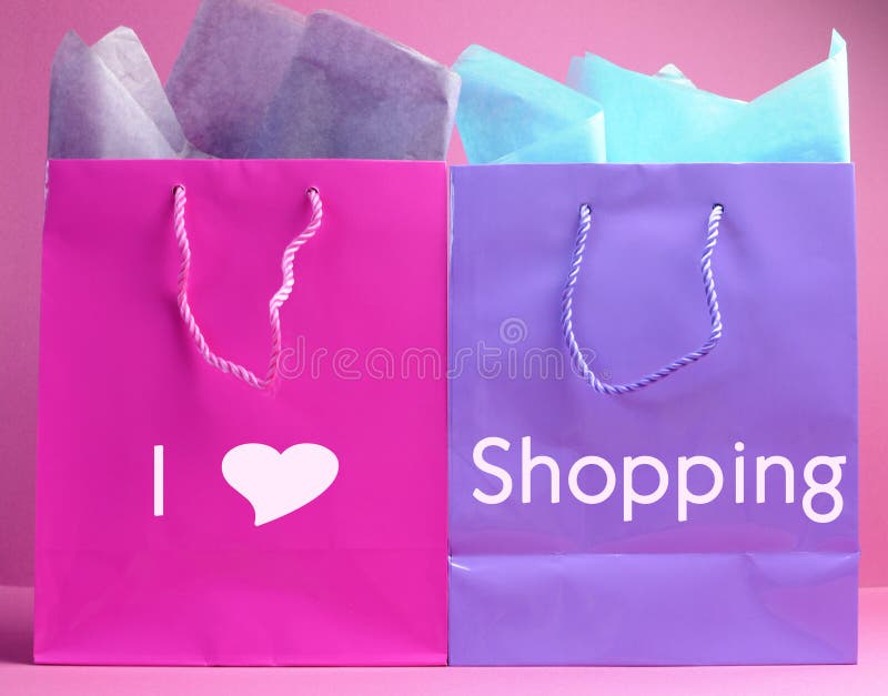 Retail therapy, I love shopping, concept with colorful pink, blue and purple shopping bags against a pink background, vertical side view. Retail therapy, I love shopping, concept with colorful pink, blue and purple shopping bags against a pink background, vertical side view.