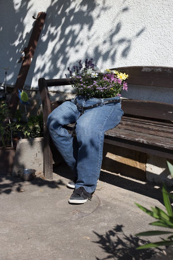 i jeans di taglio decorati con i fiori che si siedono su un giardino bench la a fotografia stock libera da diritti i jeans di taglio decorati con i fiori che si siedono su un giardino bench la a fotografia stock libera da diritti